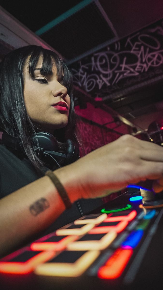 DJ na controladora durante rave, em luz neon